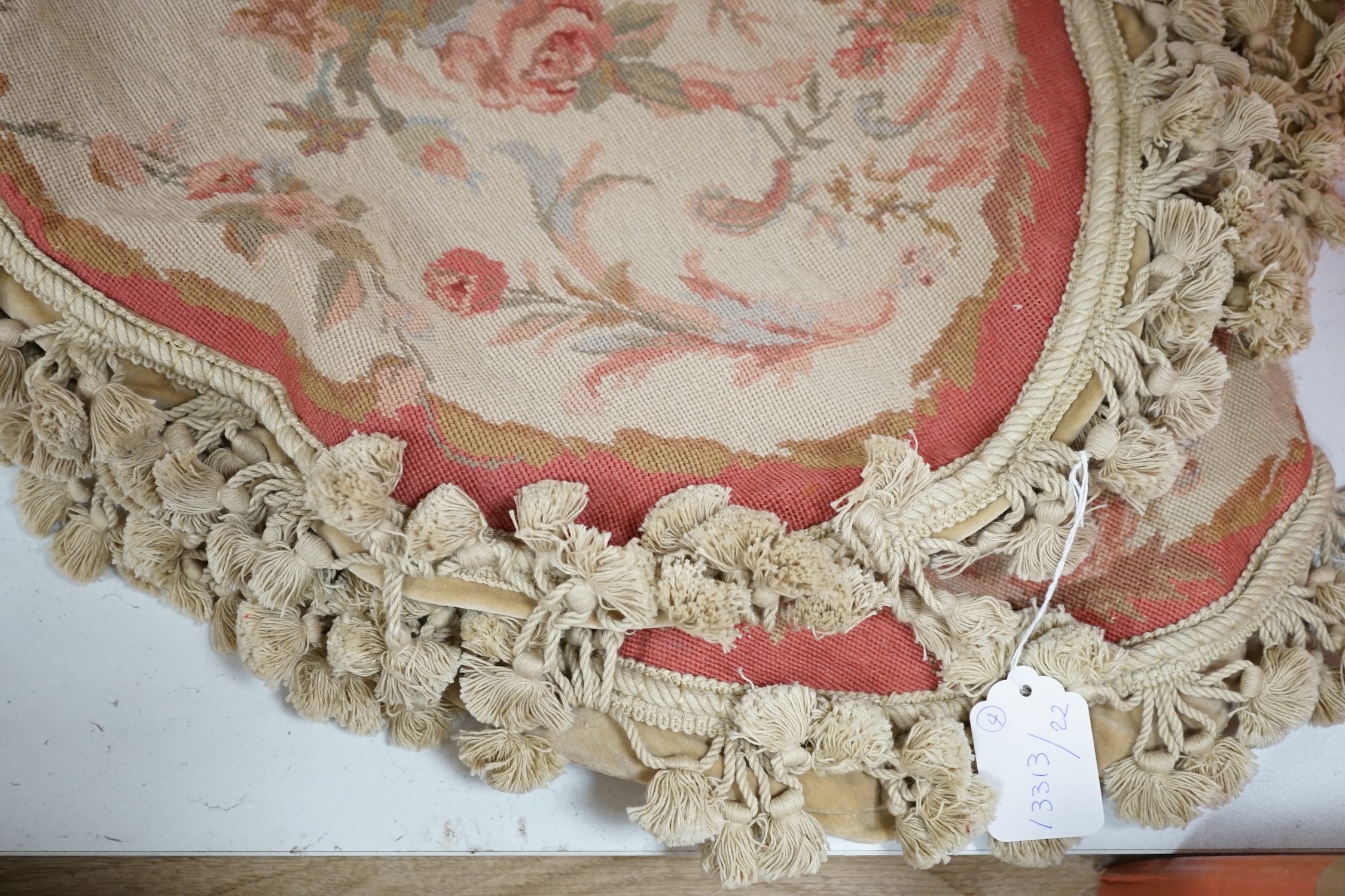 Four 20th century oval floral needleworked cushion covers with tasselled edging, 57cm wide